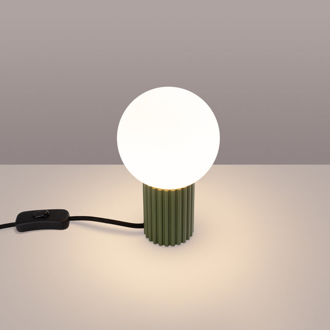 Lampe à poser Halo vert olive allumée, lumière chaude diffusée par le globe en verre opalin