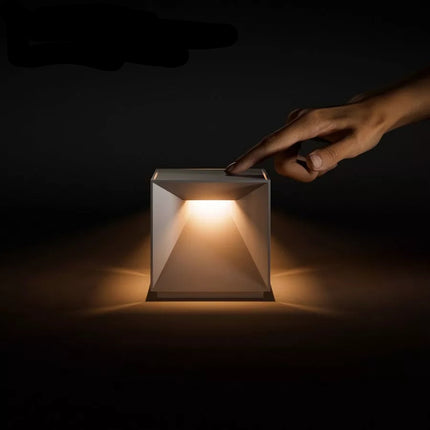 Main effleurant l'interrupteur tactile de la lampe Nutalis allumée, ambiance nocturne, lumière chaude.