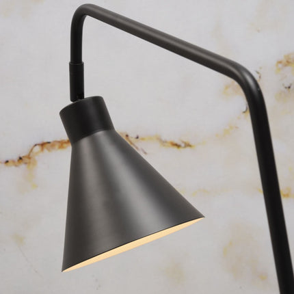 Vue rapprochée du bras coudé en fer noir de la lampe Lyon et de son abat-jour conique allumé