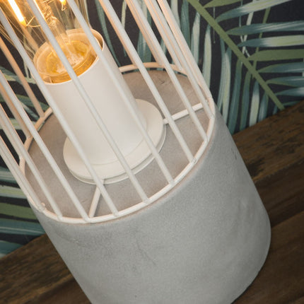 Vue rapprochée du socle en ciment et de la cage en fer blanc de la lampe à poser Memphis avec ampoule allumée