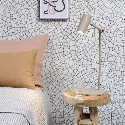 Lampe à poser Montreux sable sur une table de chevet en bois brut dans une chambre