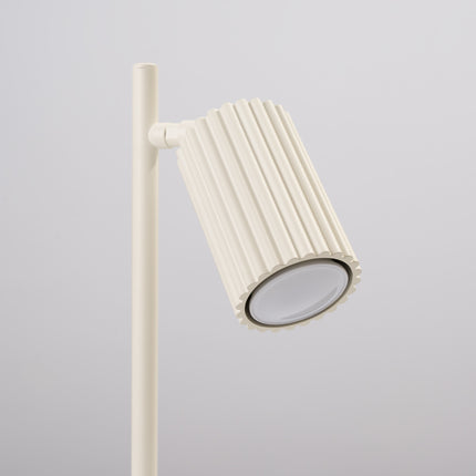 Détail de la lampe Oslo beige allumée, lumière chaude diffusée par la tête orientable