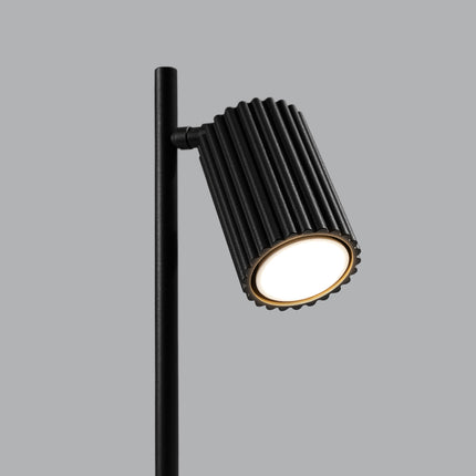 Détail de la lampe Oslo noir allumée, lumière chaude diffusée par la tête orientable