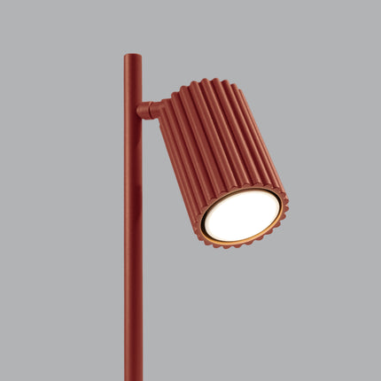 Détail de la lampe Oslo rouge ocre allumée, lumière chaude diffusée par la tête orientable
