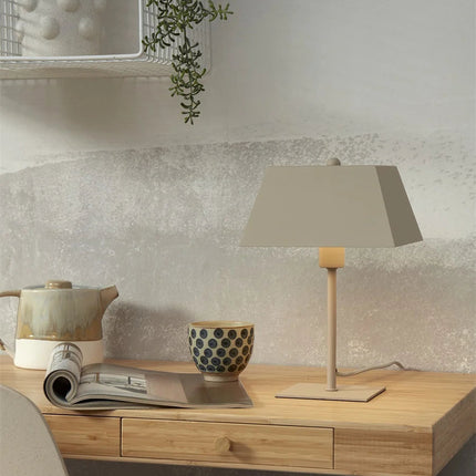 Lampe à poser Perth en fer sable posée sur un meuble en bois, abat-jour carré diffusant une lumière chaude
