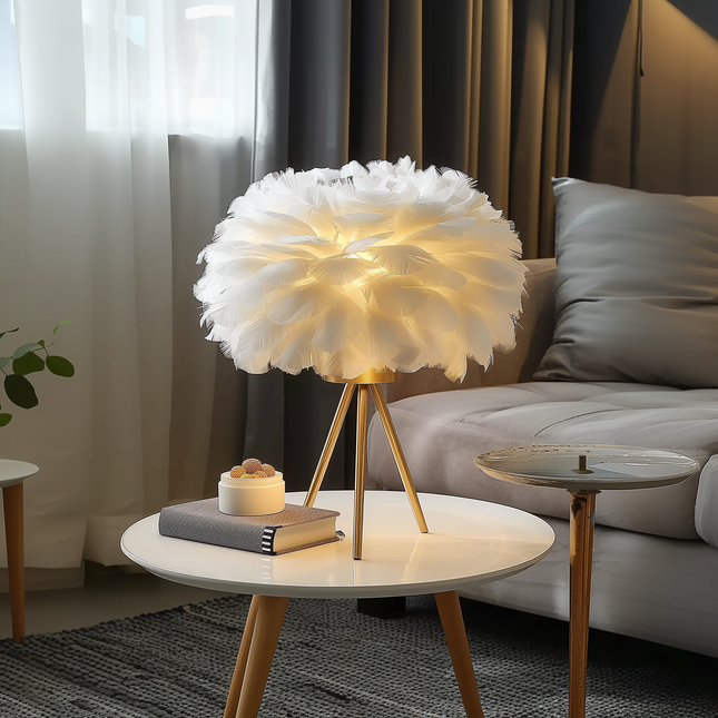 Lampe à poser abat-jour en plumes blanches sur pied tripode doré, ambiance lumineuse douce et cosy
