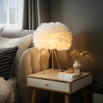 Vue d'ensemble de la lampe à poser en plumes blanches sur pied tripode doré, posée sur une table basse