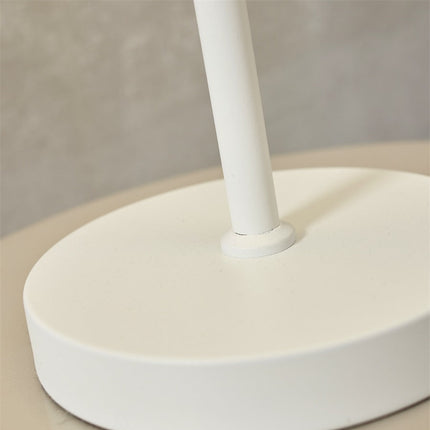 Gros plan sur la jonction entre la tige fine et la base en fer blanc de la lampe Porto