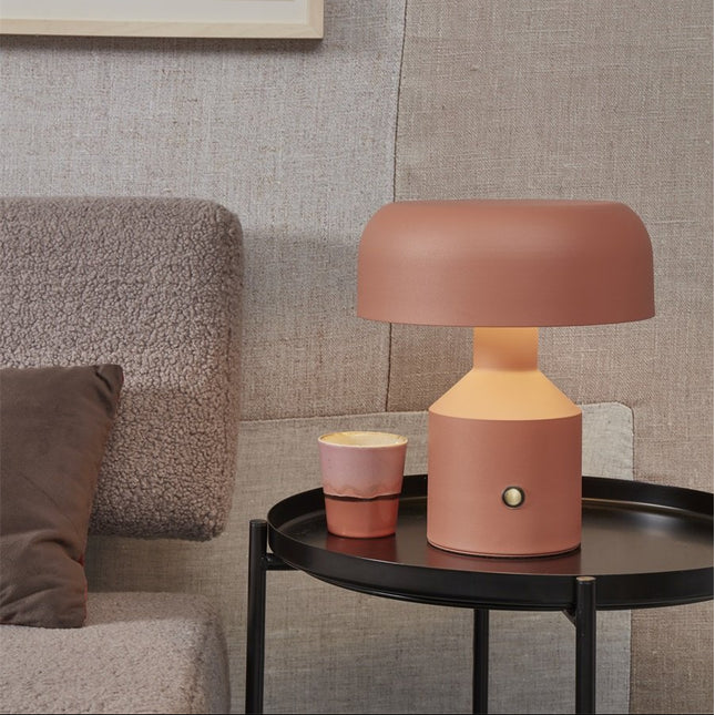 Lampe à poser Porto en fer terre cuite sur une table basse noire dans un salon cosy