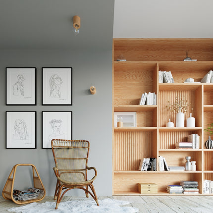 Coin lecture sur mur gris avec luminaires en bois, bibliothèque et fauteuil en rotin.