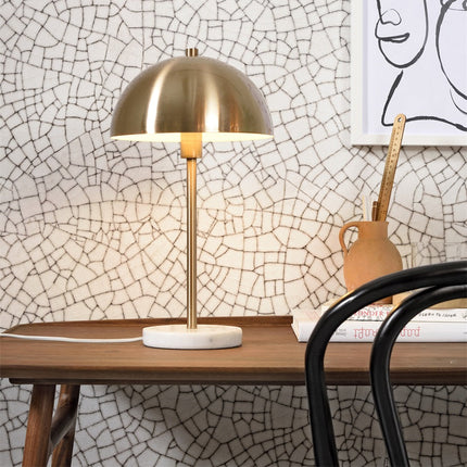 Lampe à poser Toulouse allumée sur un bureau en bois