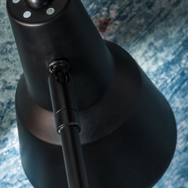 Gros plan sur la rotule et le bras articulé en fer noir mat de la lampe Valencia