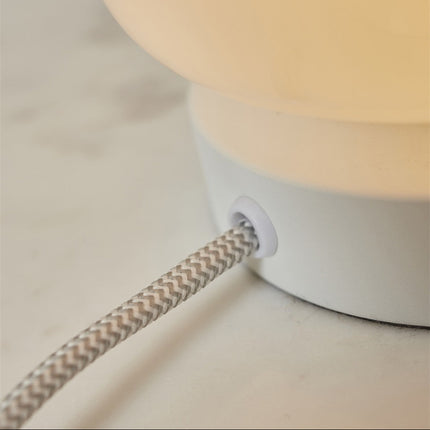 Détail du câble textile bicolore gris et blanc au pied de la lampe Verona