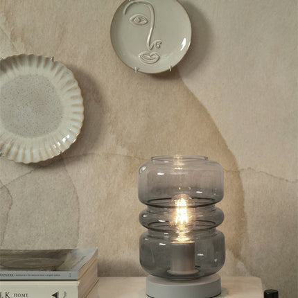 Lampe Verona allumée, ampoule visible à travers le verre fumé gris sculpté