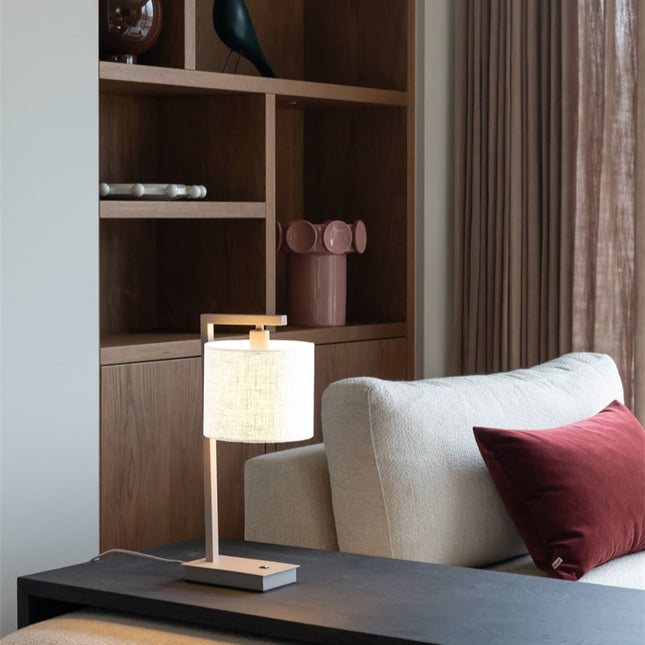 Lampe de table Boston sur un bureau, structure sable et abat-jour en coton blanc, ambiance épurée.