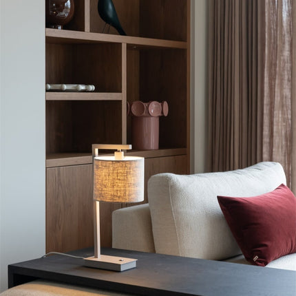 Lampe Boston posée sur une table de chevet, lumière douce diffusée par l'abat-jour lin clair.