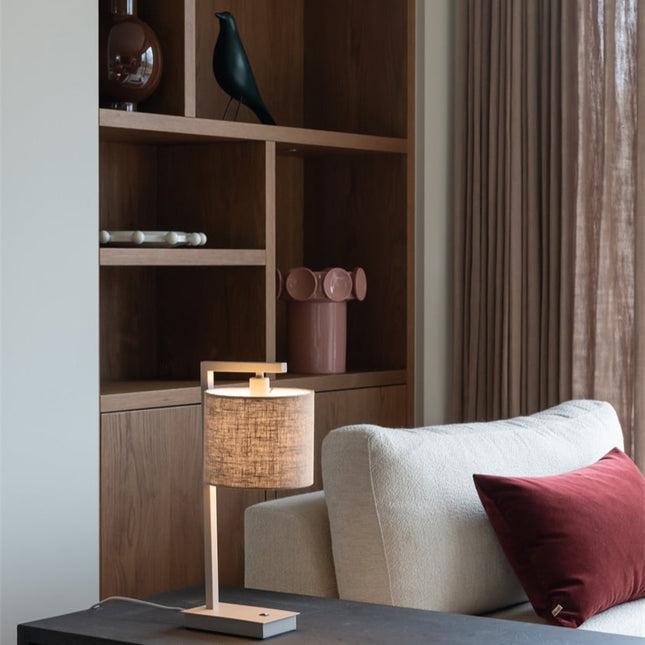 Lampe de table Boston dans un salon, structure sable et abat-jour en coton lin clair sur meuble.