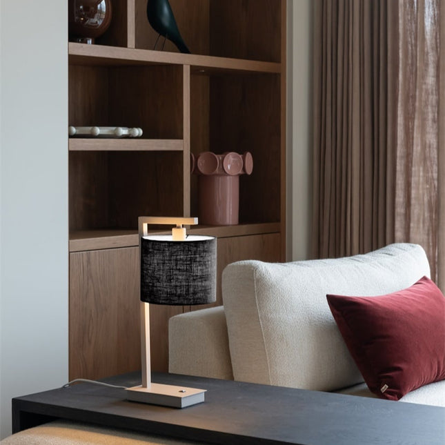 Lampe Boston posée sur un bureau en bois, ambiance chaleureuse avec abat-jour noir allumé.