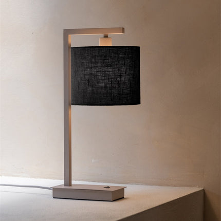 Lampe Boston sur une table de chevet, lumière douce diffusée par l'abat-jour en coton noir.