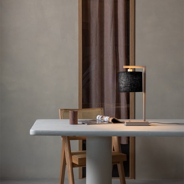 Lampe de table Boston dans un salon, structure sable et abat-jour noir posée sur une console.
