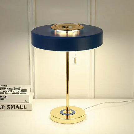 Lampe de table dorée à corps bleu posée sur une console