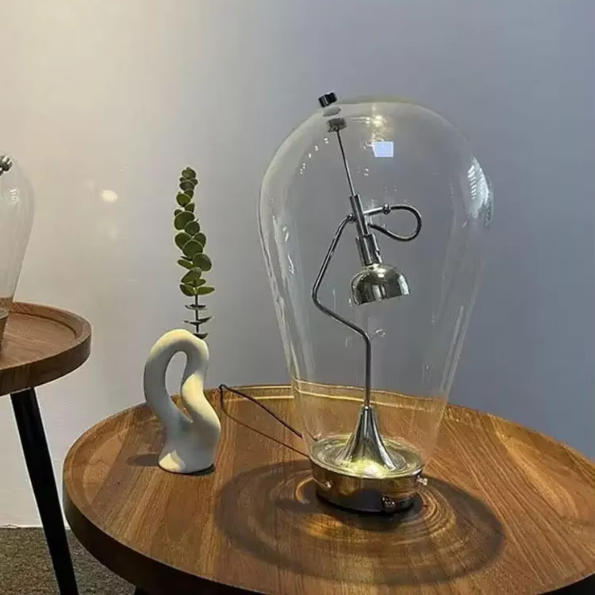 Lampe LED d'étude en verre et métal chromé, apportant un éclairage ciblé pour une surface de travail.