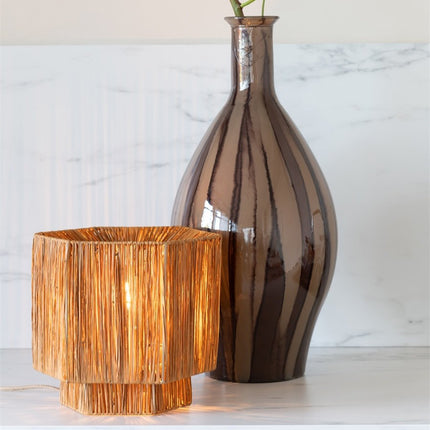 Lampe Panama allumée près d'un vase en céramique, sur un plan de travail effet marbre