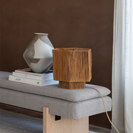 Lampe Panama allumée sur une console en bois, à côté d'un vase et de livres