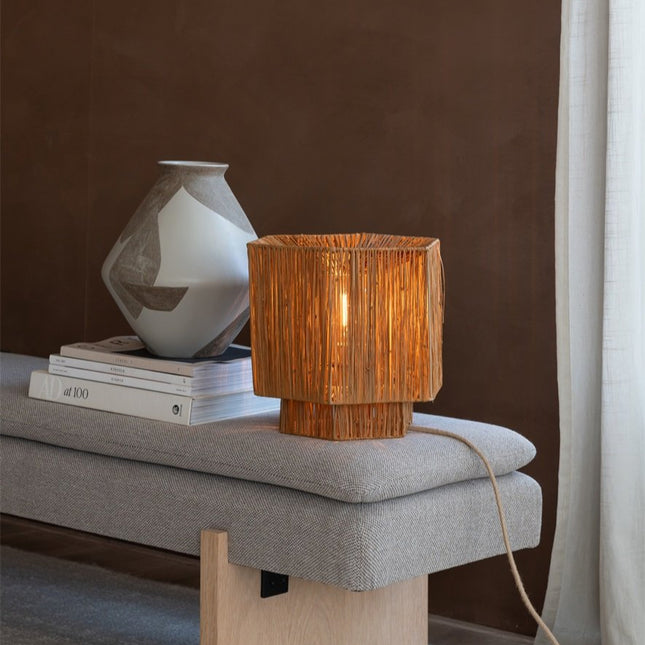 Lampe Panama allumée sur un banc en tissu, ambiance chaleureuse dans un salon