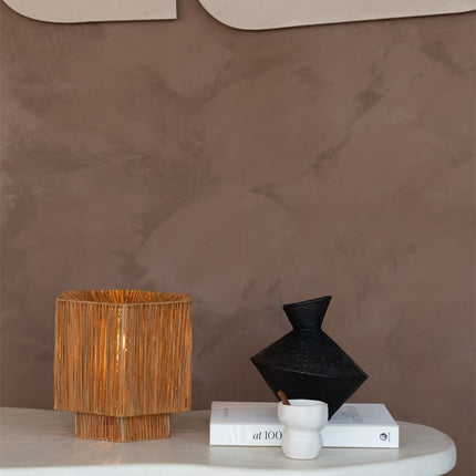 Lampe Panama allumée sur une table basse ronde, à côté d'un vase noir et de livres