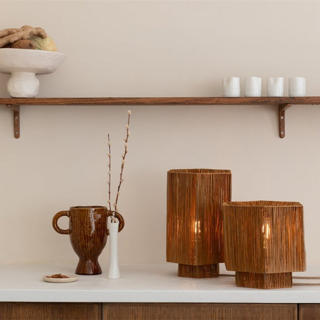 Lampes de table en raphia tressé de différentes tailles posées sur un plan de travail