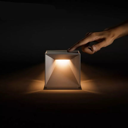 Vue trois-quarts de la lampe Nutalis, cube en aluminium allumé sur fond neutre