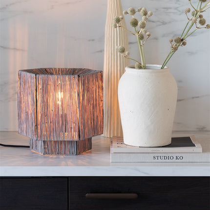 Lampe Panama allumée posée sur une console marbrée, entourée de vases en céramique