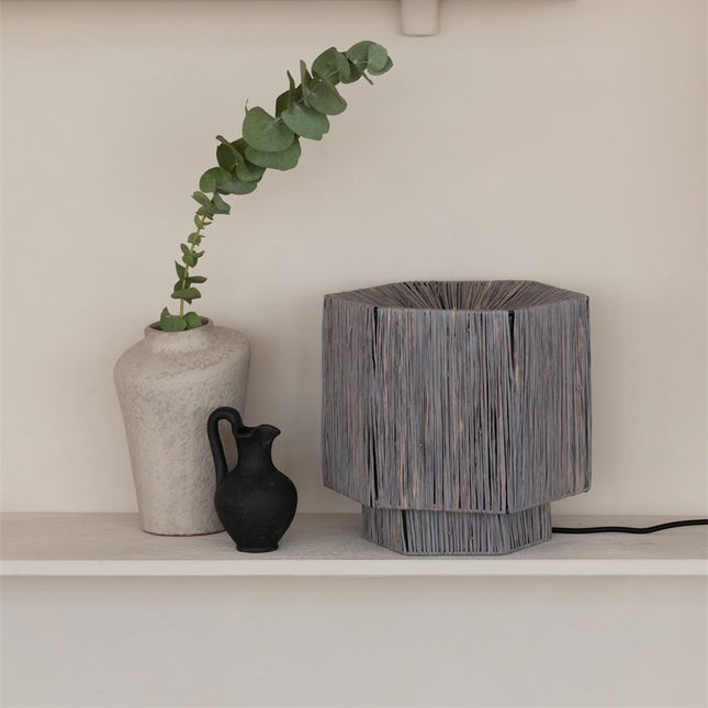 Détail de l'abat-jour en raphia gris de la lampe Panama, ambiance chaleureuse sur une étagère