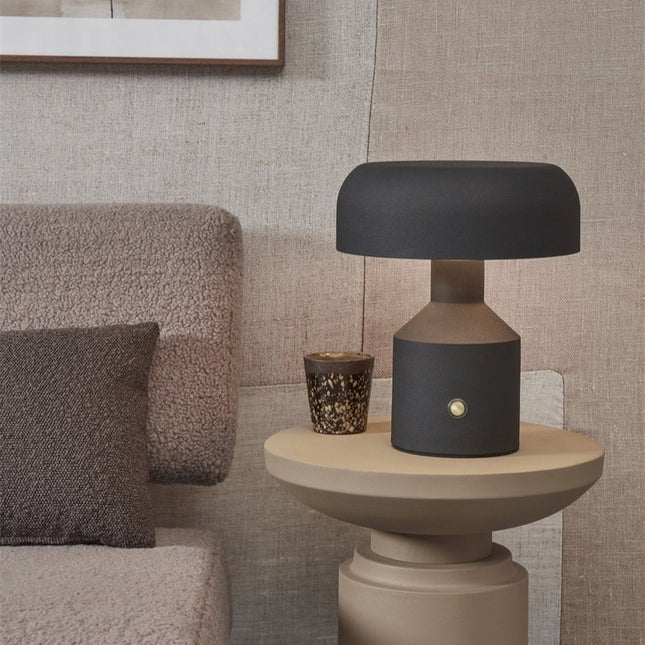 Lampe à poser Porto noire posée sur une table d'appoint dans un salon cosy