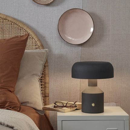 Lampe à poser Porto en fer noir allumée sur une table de chevet en chambre