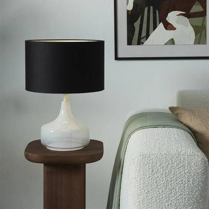 Lampe à poser Reykjavik posée sur un guéridon en bois près d'un canapé dans un salon cosy