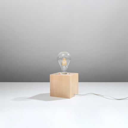 Lampe à poser cube en bois naturel sur plan blanc, ampoule filament E27 verticale, cordon blanc, éteinte.
