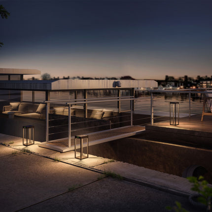 Lampes solaires Klewe Radia allumées à la tombée de la nuit sur une terrasse en bord d'eau, lumière chaude au sol