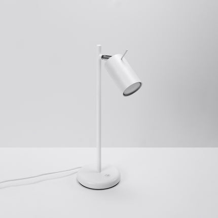 Vue de face de la lampe de table blanche, tige fine en acier et tête de spot orientée vers l'avant