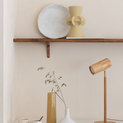 Lampe de table Java en bambou naturel dans une ambiance japandi, sous une étagère en bois avec vases et objets en céramique