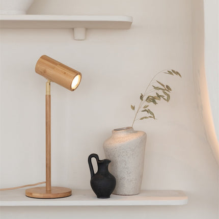 Lampe de table Java en bambou naturel sous une étagère murale, entourée de céramiques et d'un vase avec branchages secs