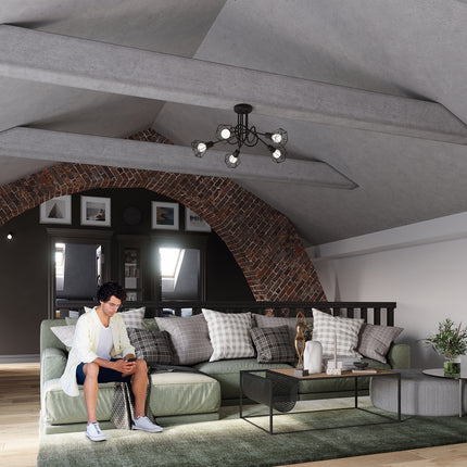 Lustre plafonnier filaire noir suspendu sous une poutre en béton, ambiance salon avec canapé vert