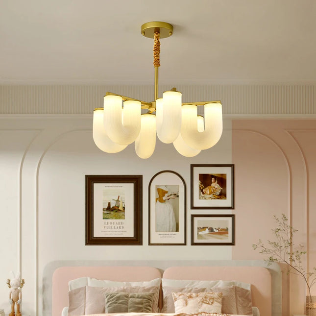 Lustre forme U aux diffuseurs opalins éclairant une chambre aux murs rose et blanc