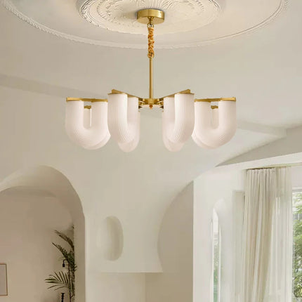 Lustre forme U doré et opalin dans une entrée nordique aux voûtes blanches lumineuses