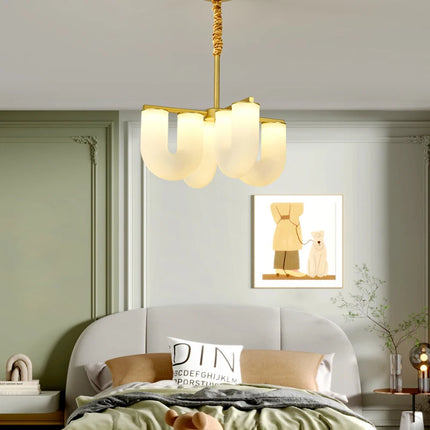 Lustre forme U opalin suspendu au-dessus d'un lit dans une chambre aux murs vert sauge