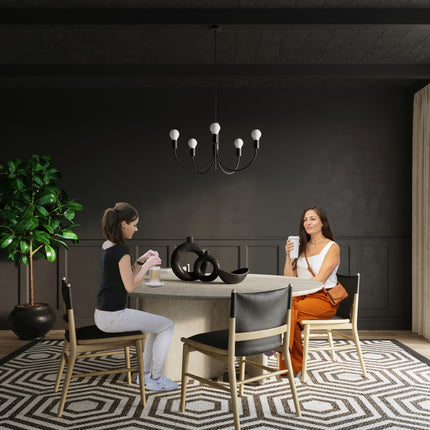 Lustre 5 bras en métal noir au-dessus d'une table à manger ronde et conviviale