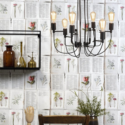 Lustre Seattle 6 bras en fer noir mat suspendu devant un mur habillé de motifs botaniques