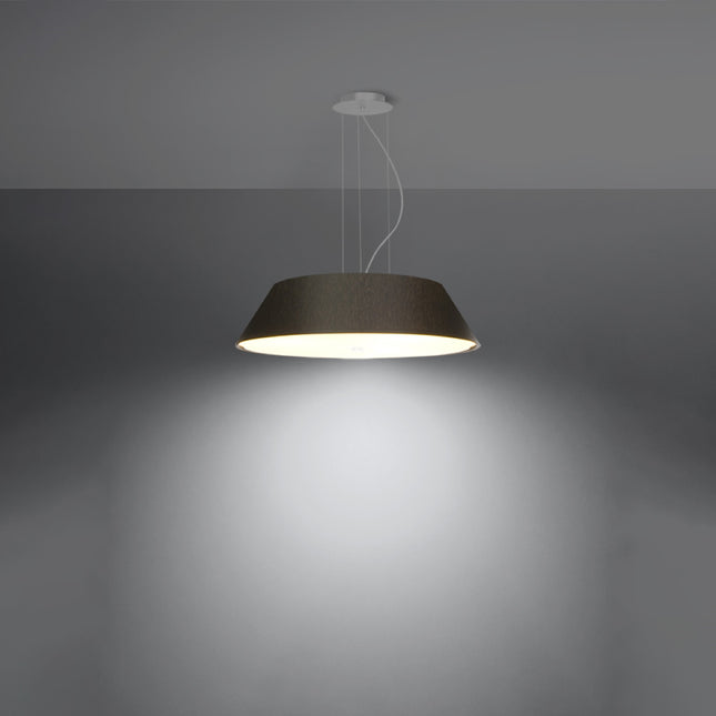 Lustre Trapèze en tissu noir allumé diffusant une lumière chaude et homogène vers le sol dans une ambiance sombre