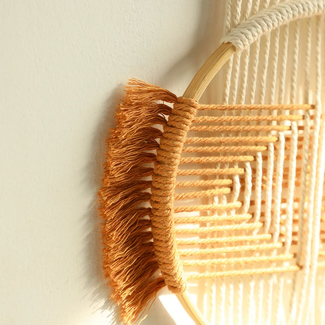 Gros plan sur le motif géométrique tissé main et les franges terracotta du macramé rond